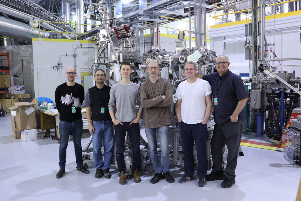 Our Technical Operations team pose in front of shiny, metallic research equipment at the Quantum Materials Spectroscopy Centre at the Canadian Light Source